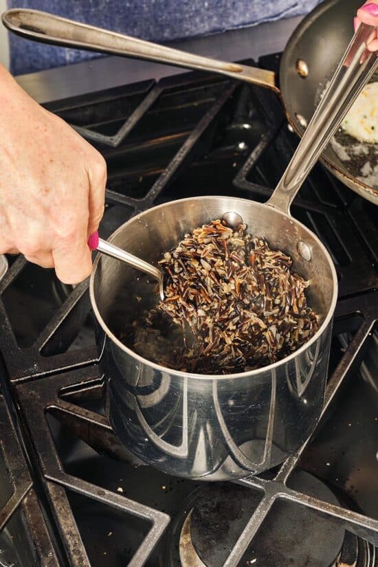 Woman stirring a pot of Wild Rice on the stove.