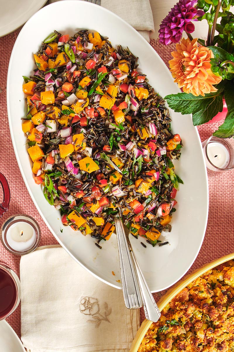 Spoon in a bowl of colorful Wild Rice and Sweet Potato Salad.