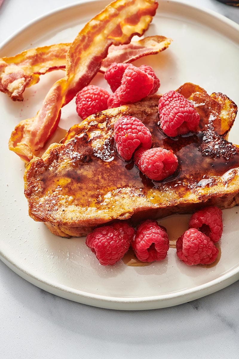 Challah French Toast topped with raspberries and syrup.