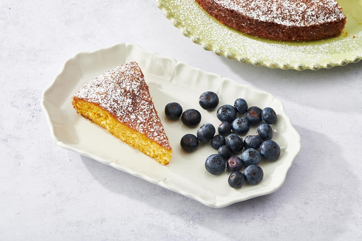 Slice of Orange Cake and blueberries on a white plate.
