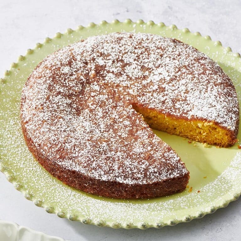 Orange Cake missing a slice on a green plate.