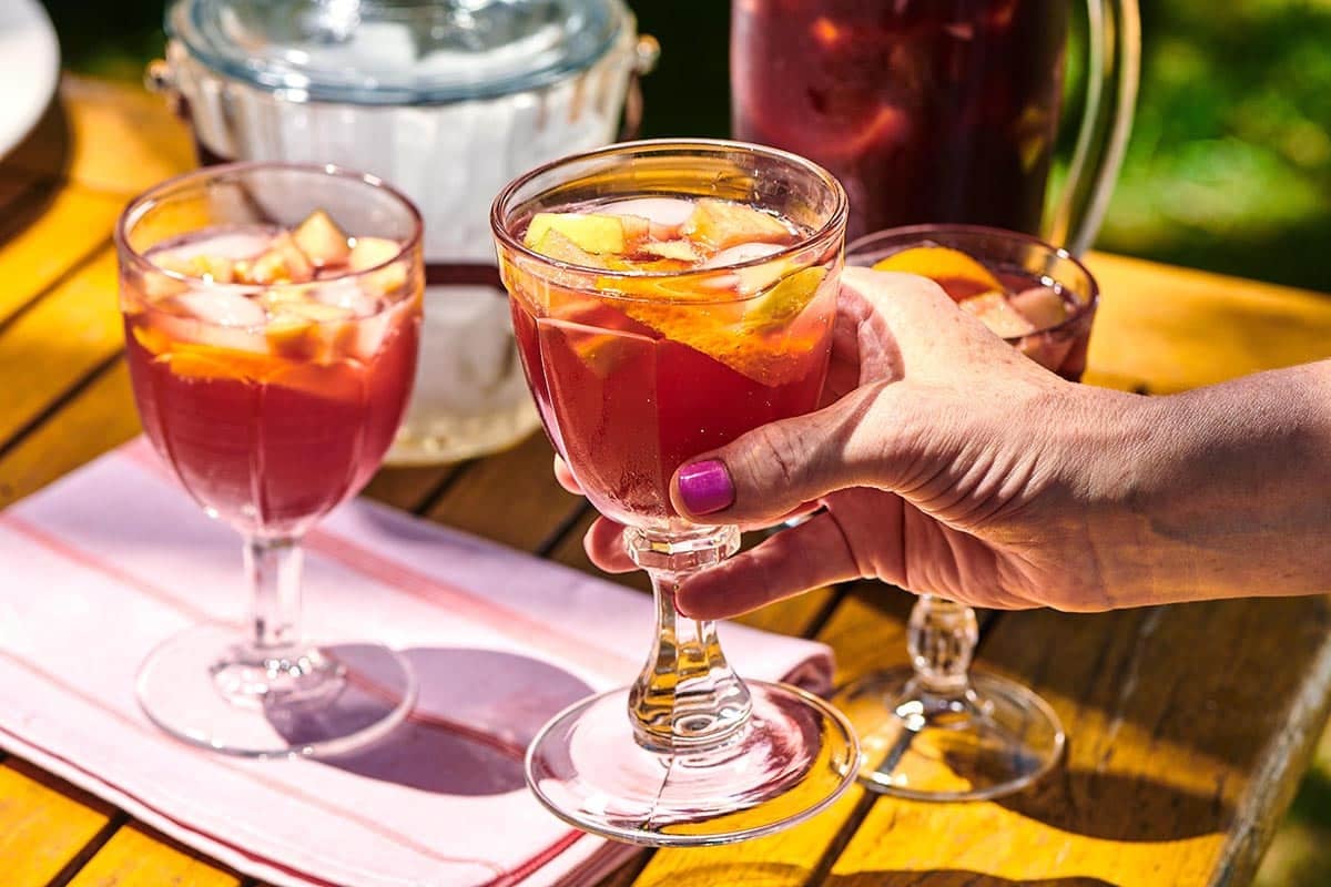 Woman holding a long-stemmed glass of Red Sangria.