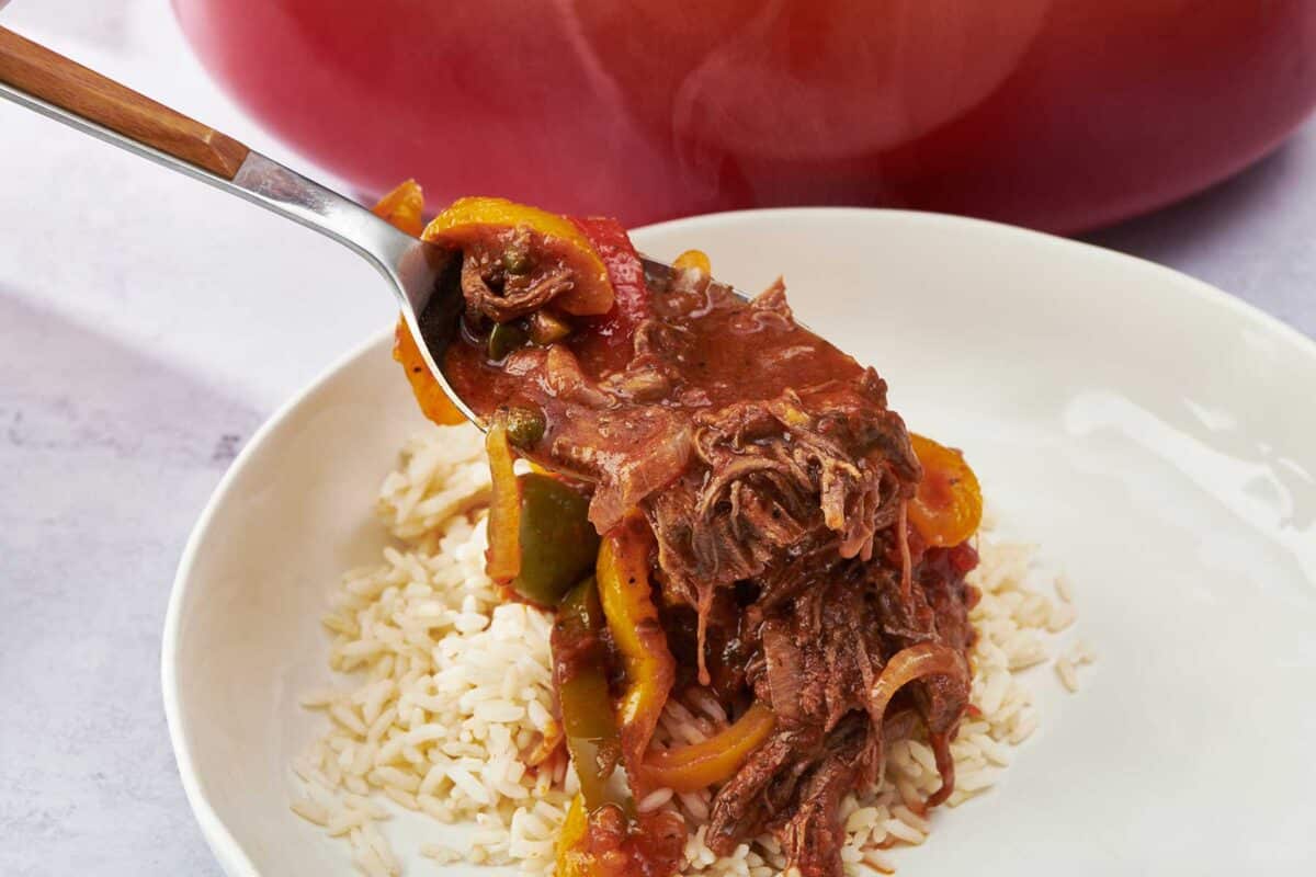 Fork placing Ropa Vieja on a bed of rice.