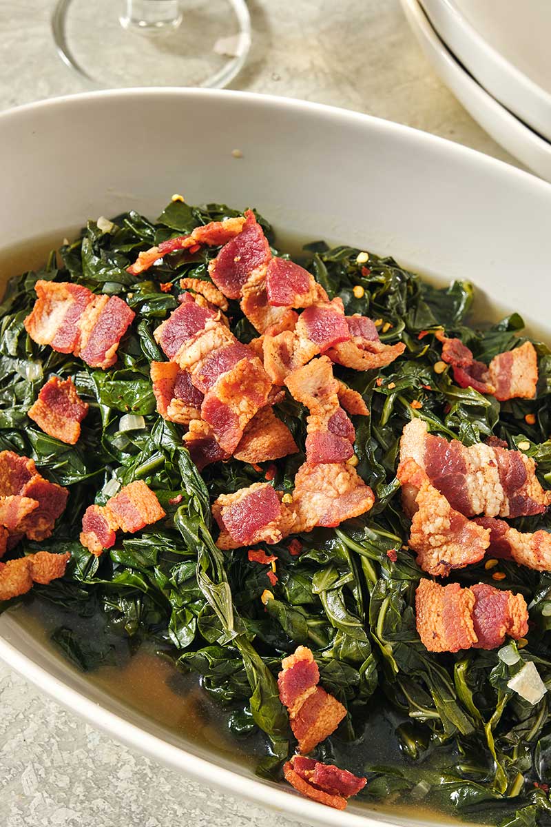 Bacon on top of a bed of collard greens.