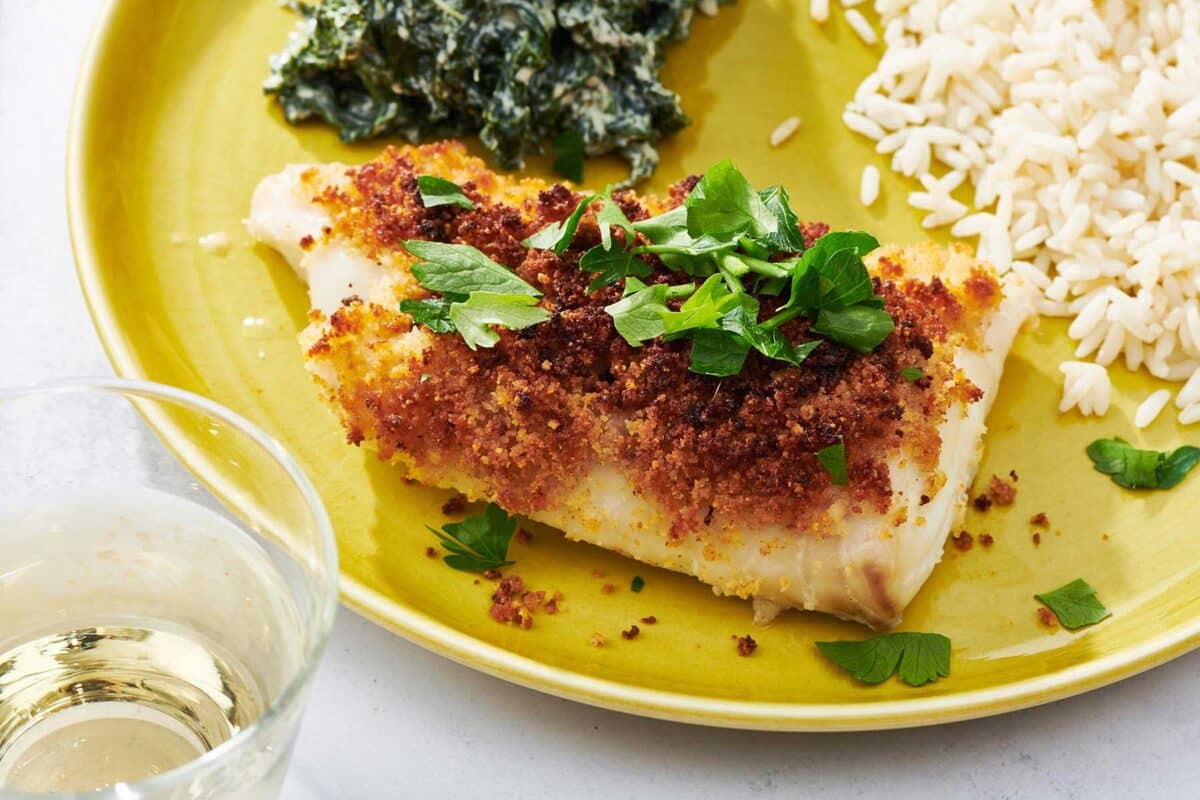 Baked Haddock garnished with fresh parsley on yellow plate.