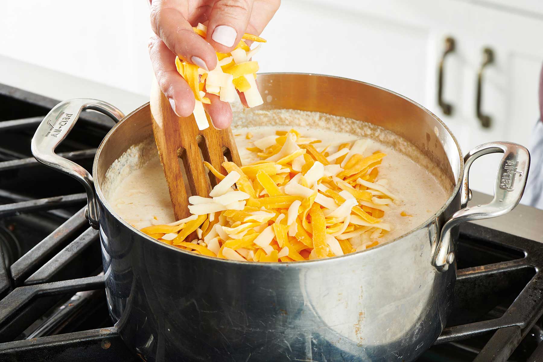 Adding cheese to large soup pot.