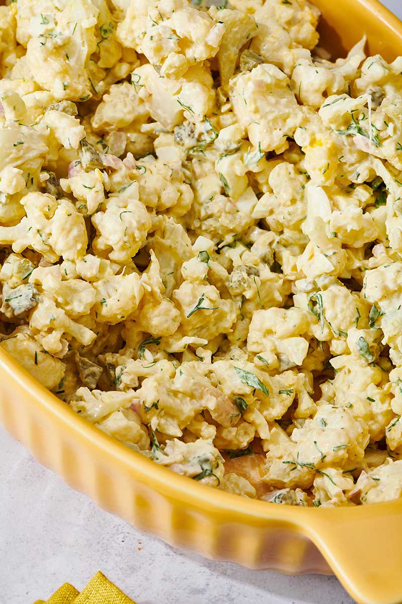 Yellow dish filled with Cauliflower Potato Salad.