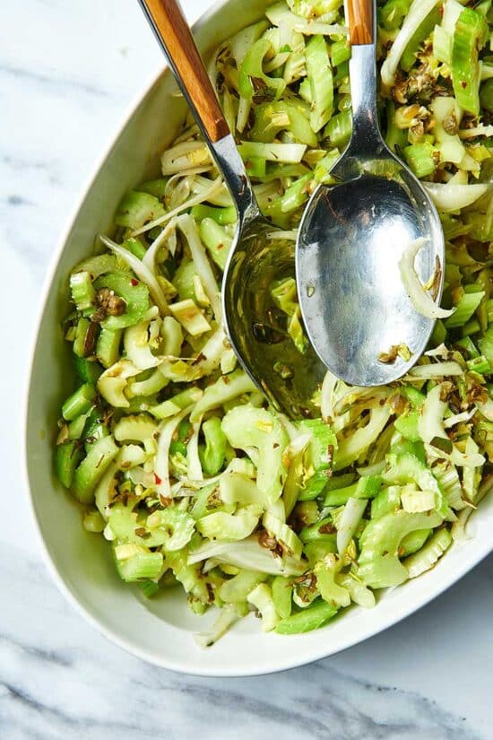 Celery Salad in white bowl with serving spoons