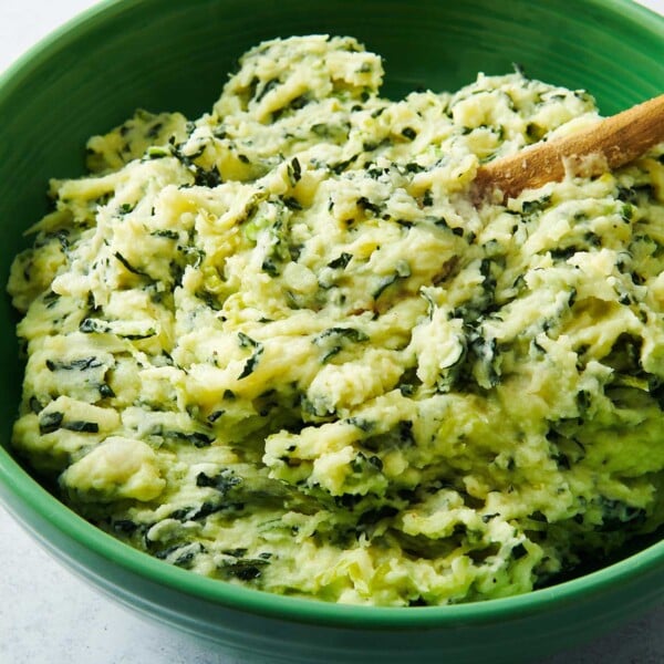 Wooden spoon in a green bowl of Colcannon.