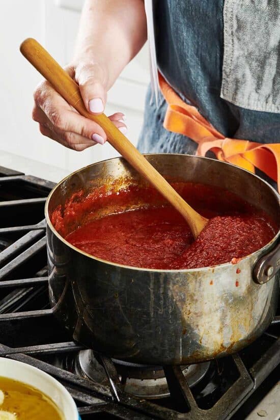 Stirring pot of homemade marinara sauce with wooden spoon