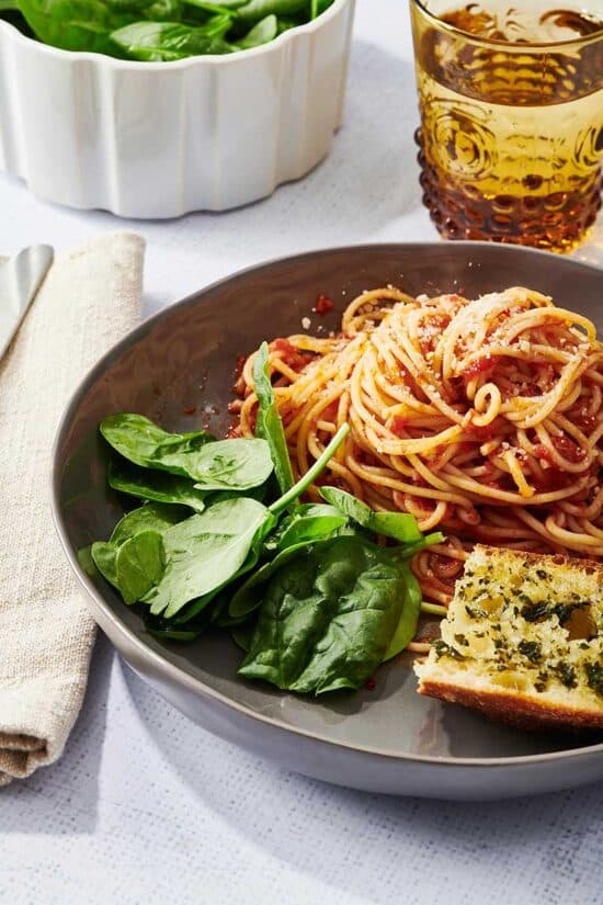 Plate of spaghetti with homemade marinara sauce, lettuce, and garlic bread