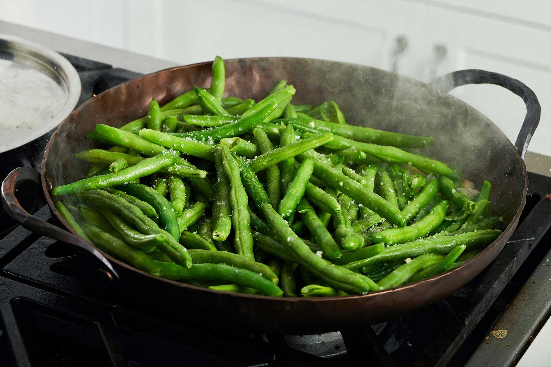 Steam coming off of a skillet of green beans.