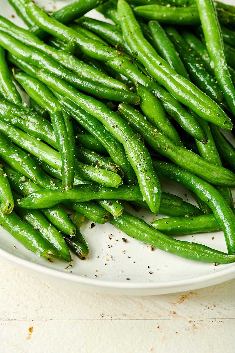 Seasoned green beans on a white plate.