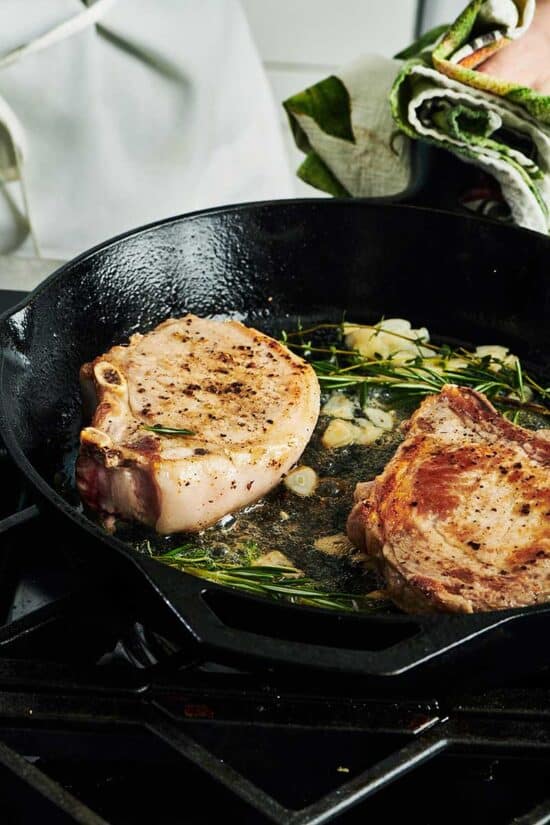 Frying pork chops on the stovetop with rosemary and garlic
