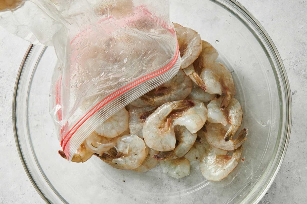 Shrimp being poured from a bag into a glass bowl.