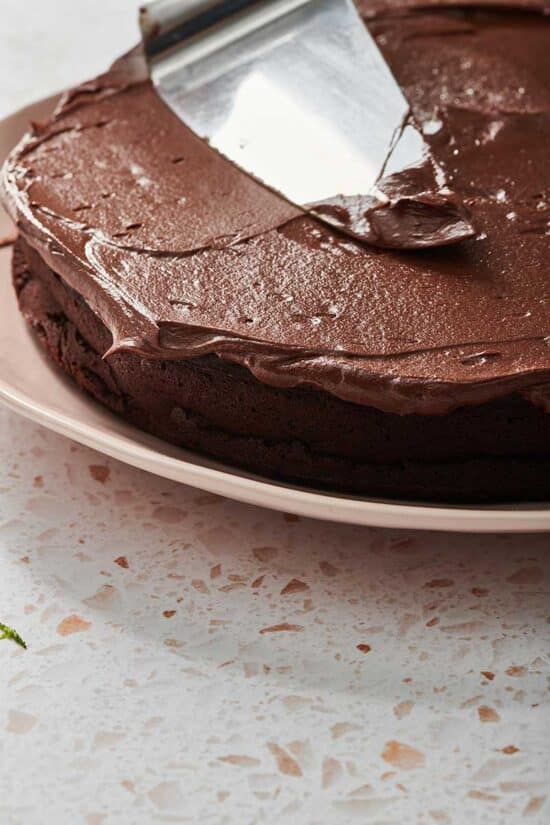 Spreading chocolate ganache over chocolate cake