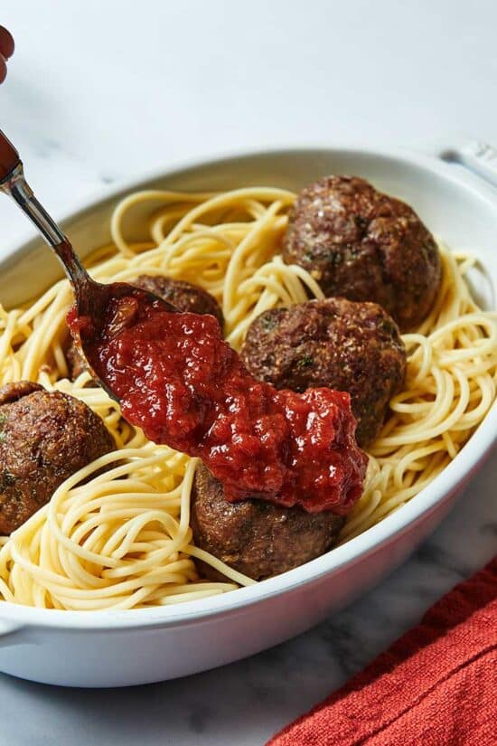 Spreading a platter of Jumbo Meatballs and spaghetti with marinara sauce