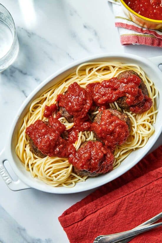 Baked Jumbo Meatballs over spaghetti topped in marinara sauce in a white platter