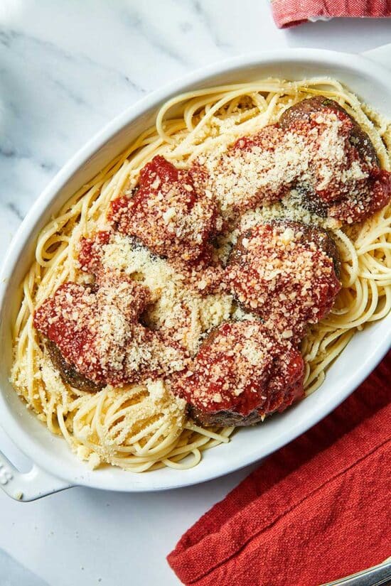 Jumbo Meatballs on white platter with spaghetti, marinara, and Parmesan.