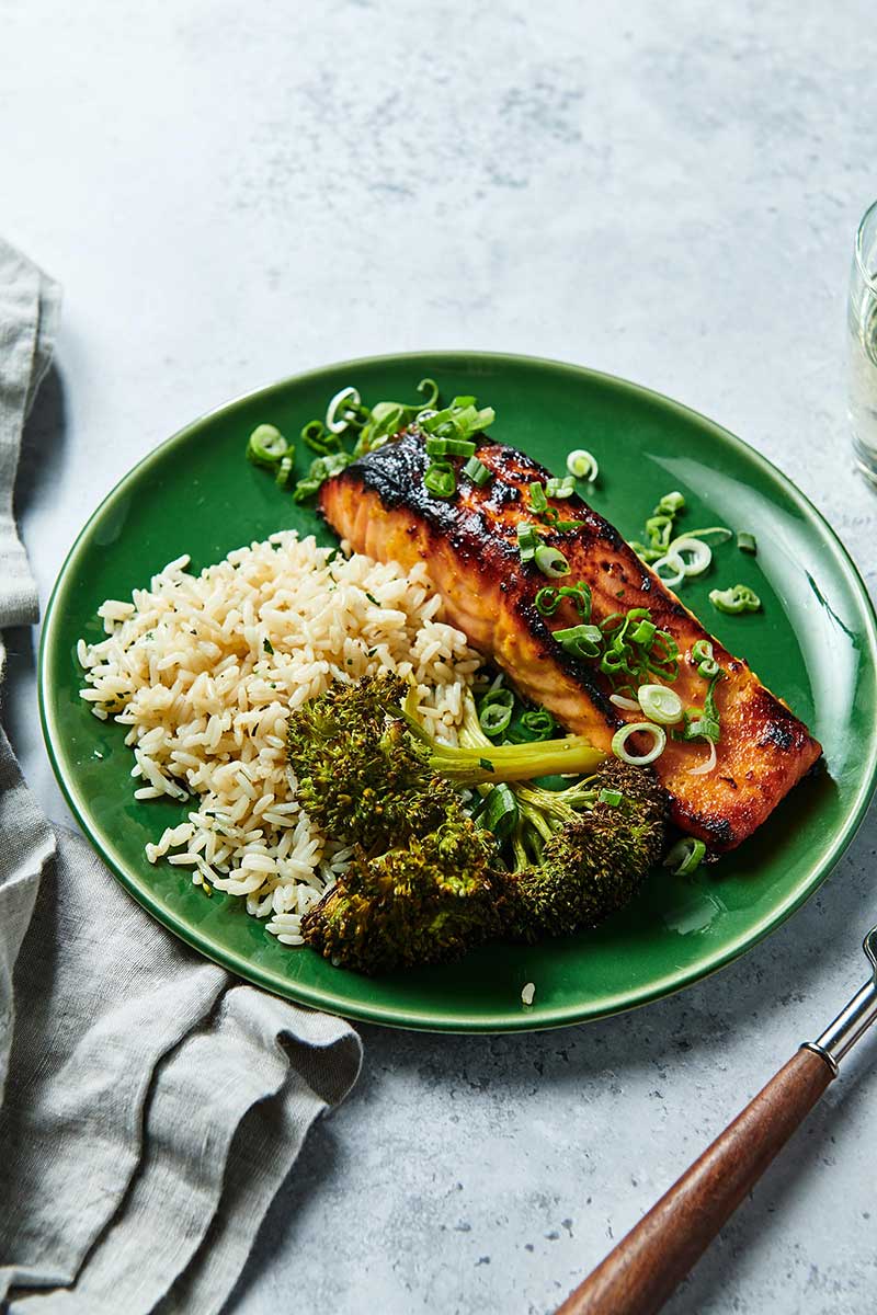 Miso-marinated salmon on green plate with broccoli and rice.