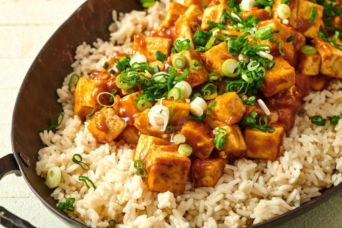 Orange Tofu on a bed of rice in serving dish.