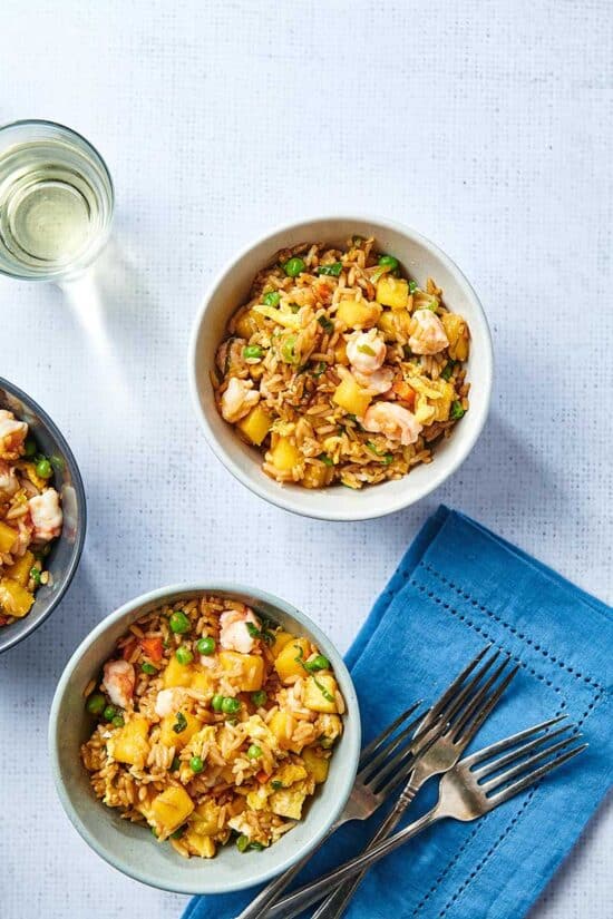 Bowls of Pineapple Shrimp Fried Rice with table setting and wine