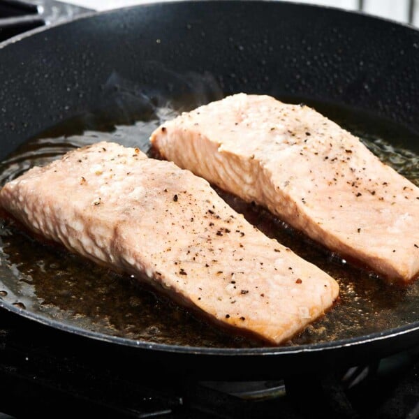 Cooking salmon filets in pan on stove.