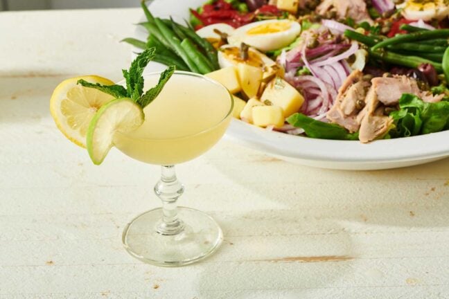 Sparkling Limoncello Cocktail in a long-stemmed glass next to a colorful salad.