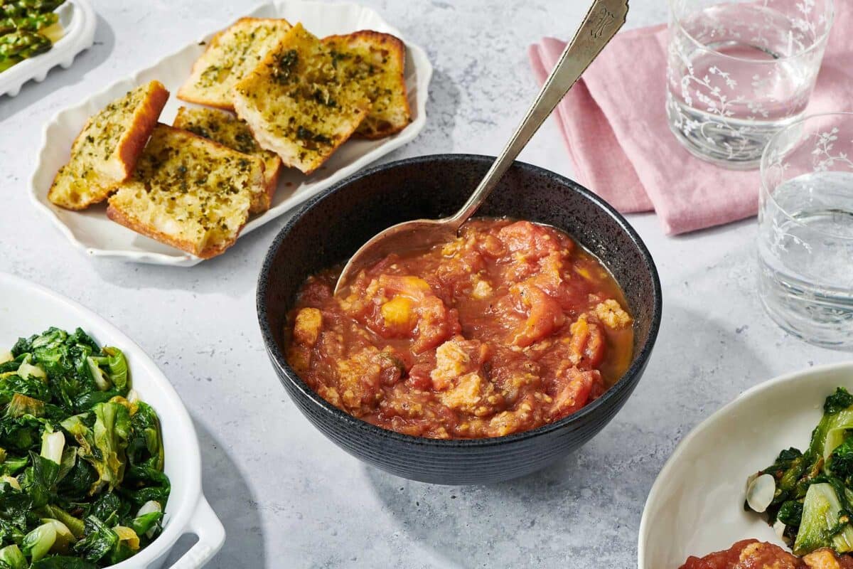 Stewed Tomatoes in dark grey bowl on table.