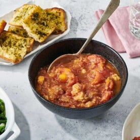 Stewed Tomatoes in dark grey bowl on table.