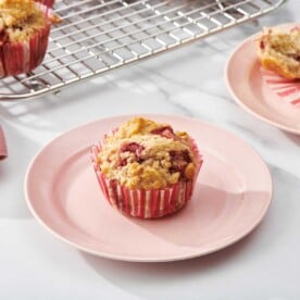 Strawberry Muffins on small pink plates and a wire rack.