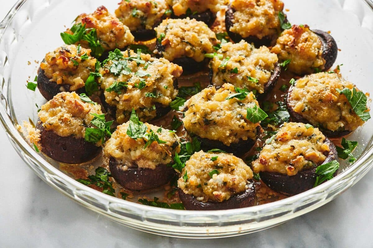 Glass bowl of Stuffed Mushrooms topped with chopped parsley.