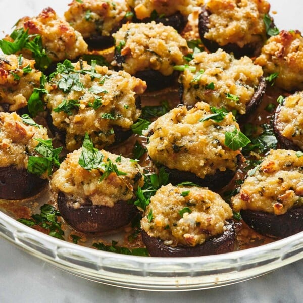 Glass bowl of Stuffed Mushrooms topped with chopped parsley.