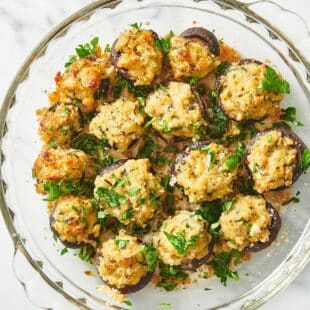 Stuffed Mushrooms in a glass bowl on a marbled table.