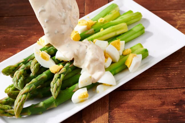 Spooning remoulade sauce over asparagus