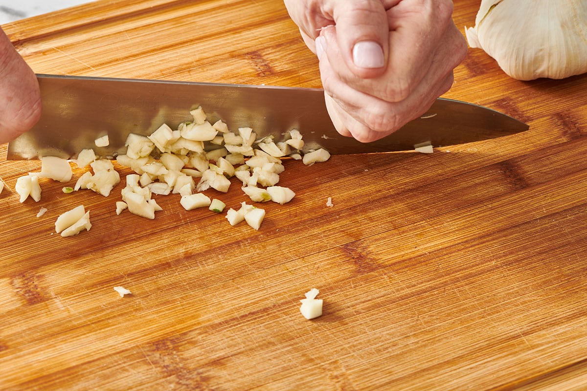Chopping fresh garlic with chef knife.