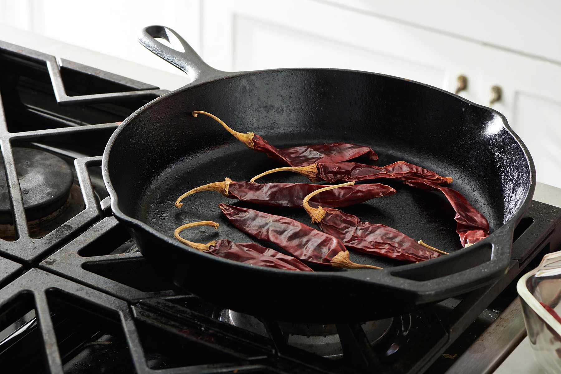 Toasting chile peppers in cast-iron pan on the stove.