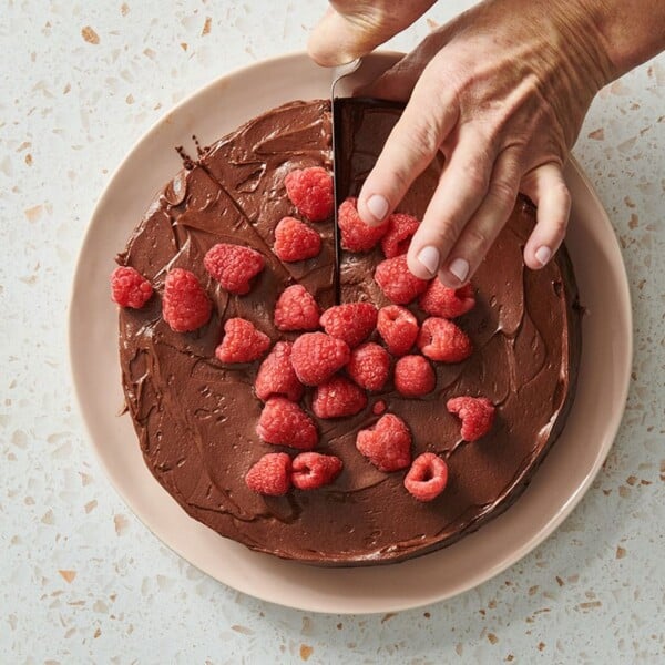 Slicing Nut-Free Flourless Chocolate Cake on plate.