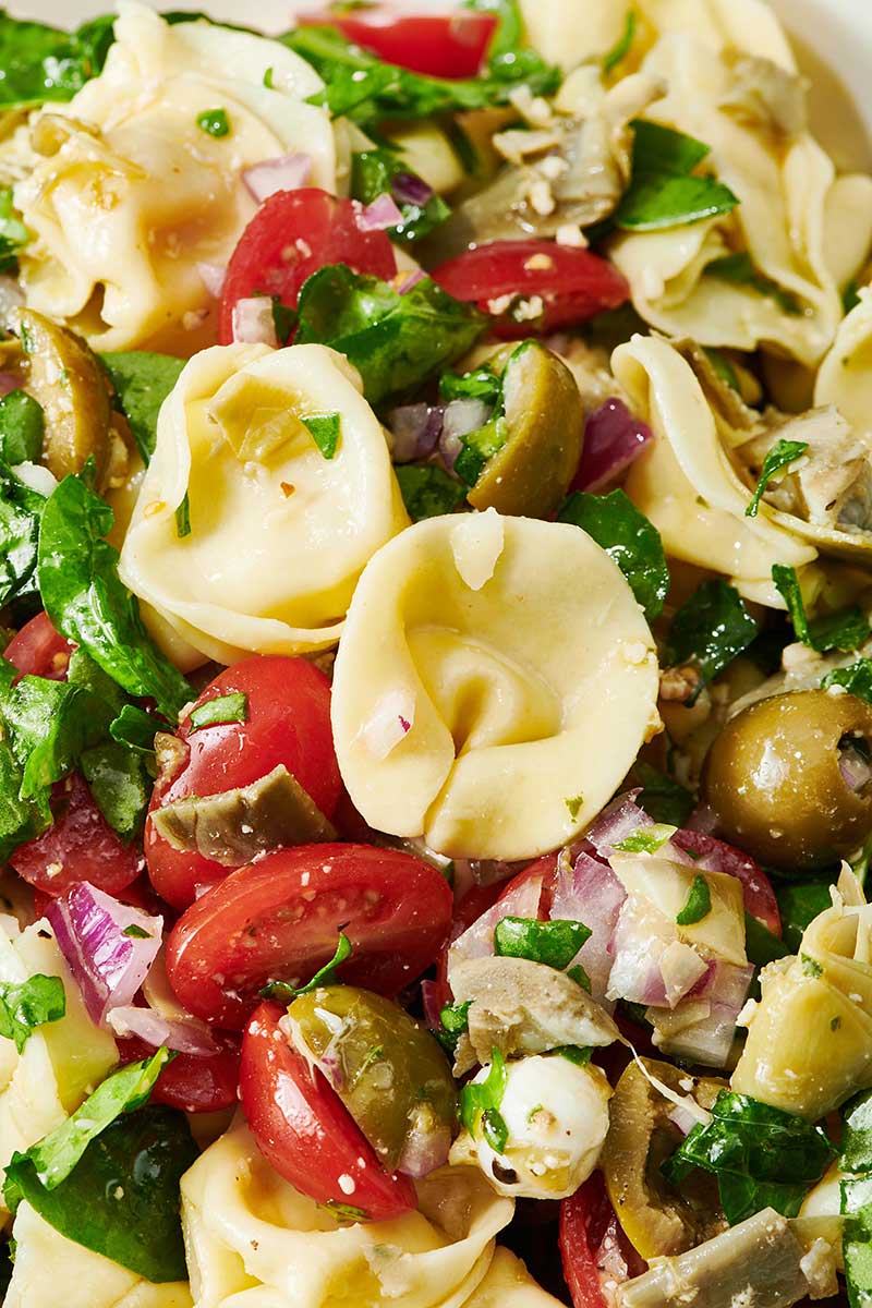 Tortellini Pasta Salad with olives, artichoke, spinach, and mozzarella balls.