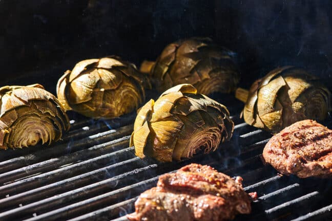 Artichokes and burgers cooking on grill