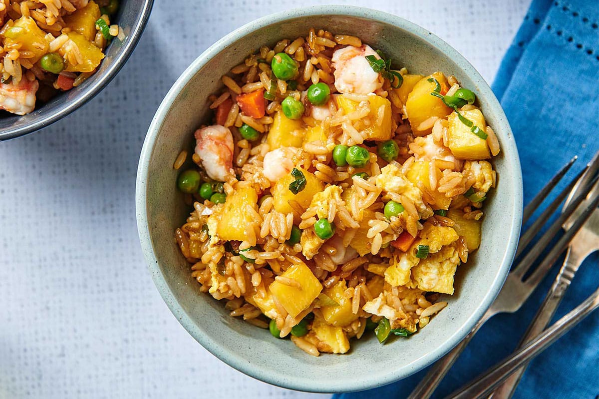 Pineapple Shrimp Fried Rice in blue bowl on table.