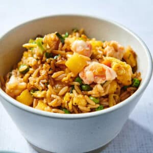 Fried rice with pineapple and shrimp in white bowl on table.