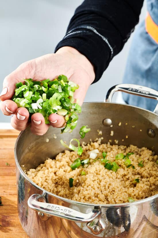 Adding scallions to pot of quinoa