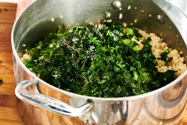 Fresh chopped herbs in pot of cooked quinoa