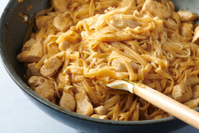 Stirring rice noodles and stir-fried chicken in wok