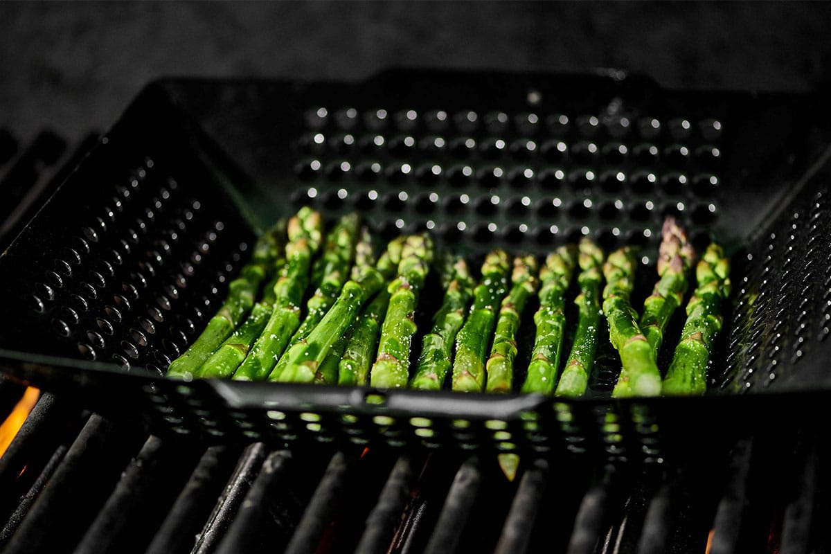 Grilling asparagus in basket.