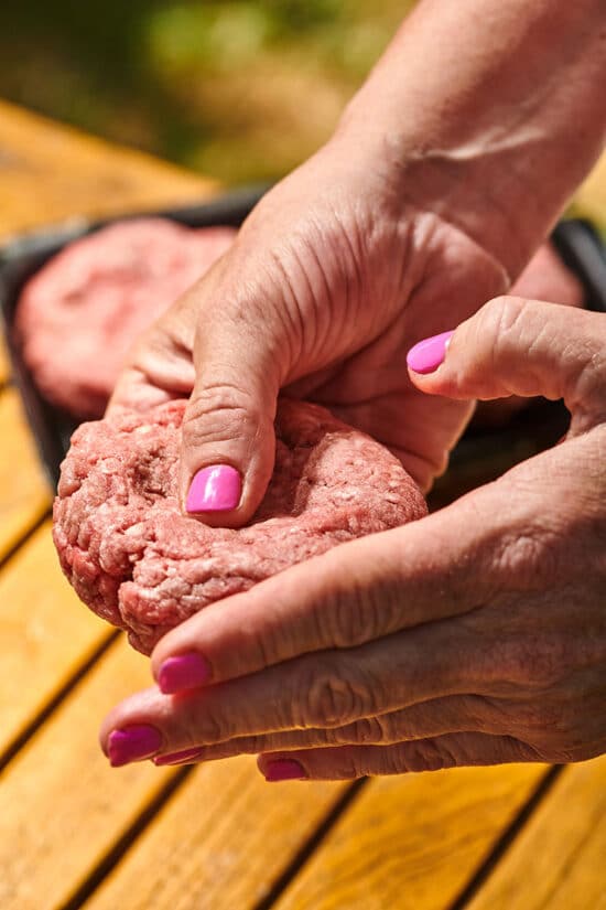 Woman pressing fresh hamburger patty
