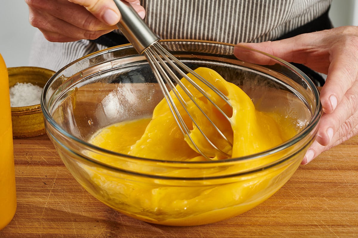 Beating eggs in bowl with whisk.