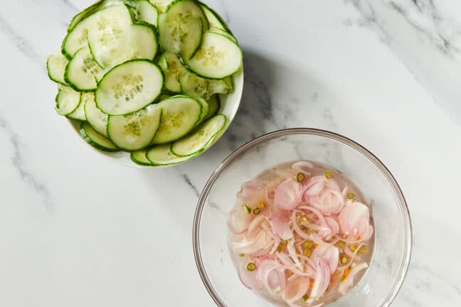 Sliced cucumbers and marinating shallots in bowls 
