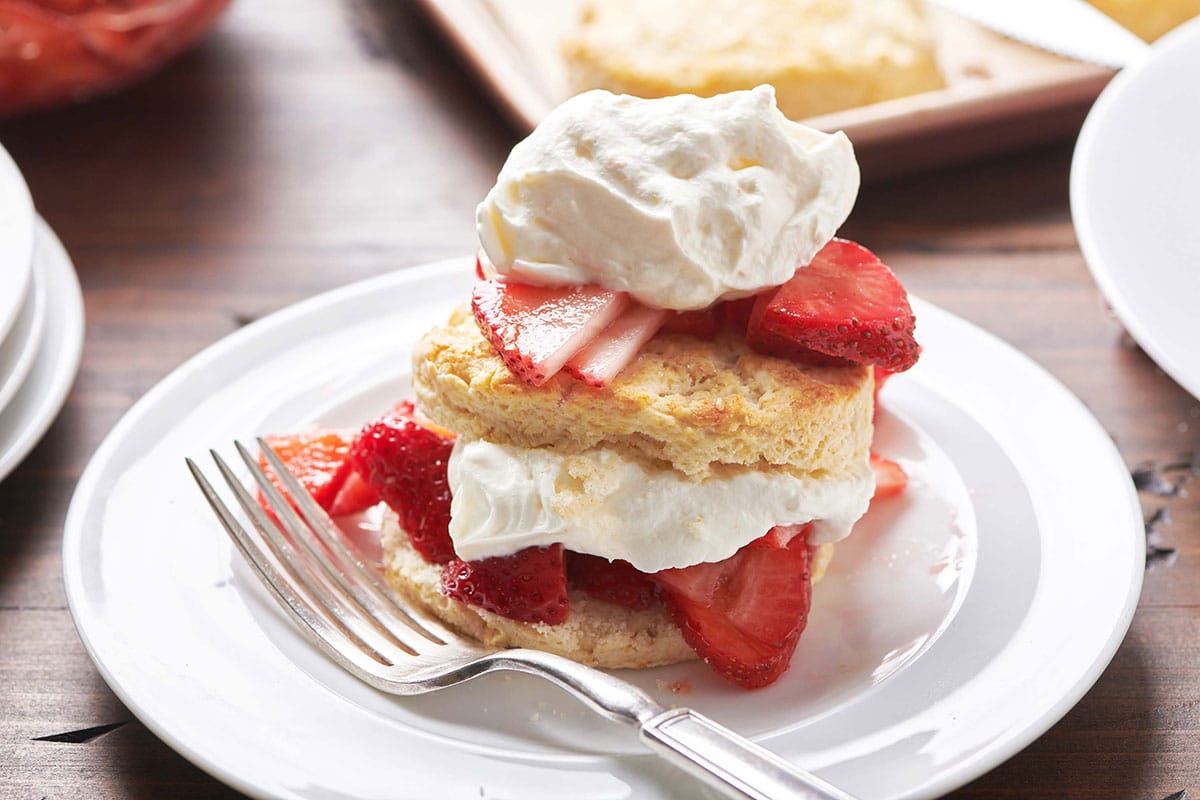 Plate with two repeating layers of biscuit, strawberries, and whipped cream.